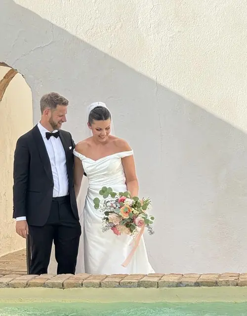 Bride and groom with bouquet by pool